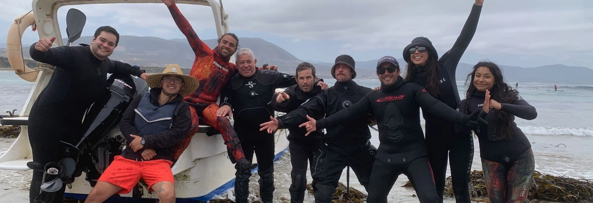 Grupo de buzos celebrando junto al bote en la playa de Los Molles