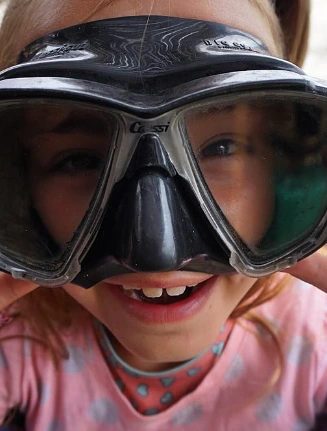 Niña pequeña jugando con una máscara de buceo