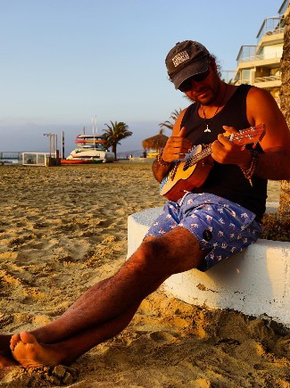Instructor tocando el ukelele en la playa al atardecer